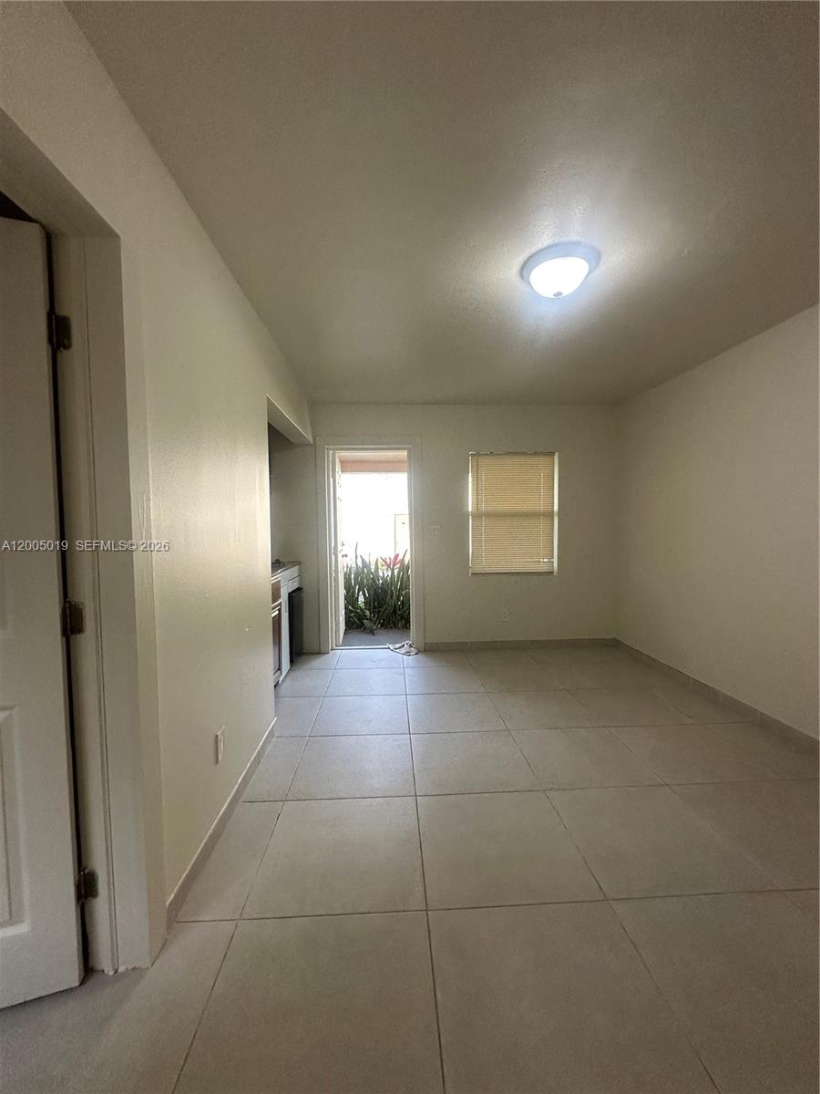 This room features light-colored tile flooring, white walls, a ceiling light, and an exterior door — 1708 Van Buren St # 3, Hollywood FL 33020, HOLLYWOOD, FL