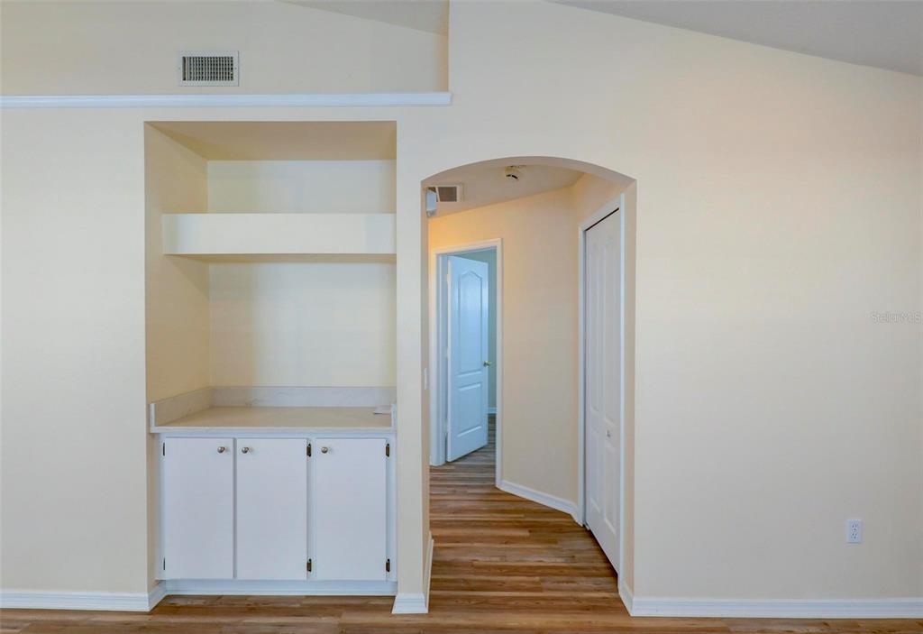 A room with a built-in cabinet and shelving unit next to an arched hallway entrance — 18105 LEMBRECHT WAY, TAMPA, FL