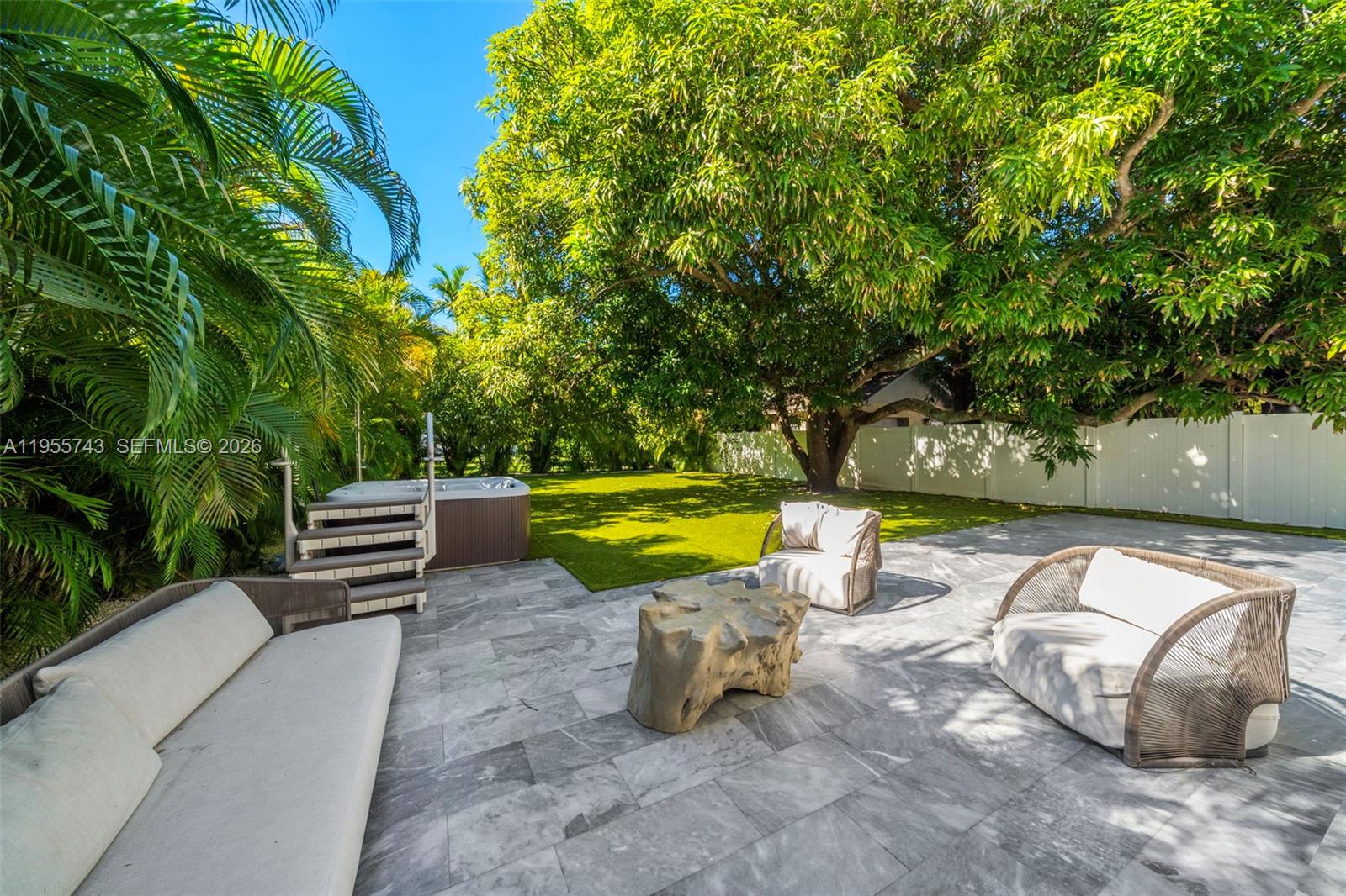 A patio with stone tiles, outdoor furniture, a hot tub, and a large tree — 3166 Royal Palm Ave, Miami Beach FL 33140, MIAMI BEACH, FL