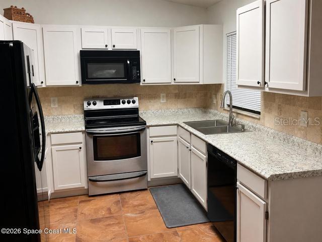 A kitchen features white cabinets, stainless steel appliances, granite countertops, and tiled flooring — 3665 SE 137TH LANE, SUMMERFIELD, FL