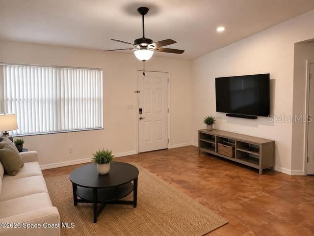 A living room features a ceiling fan, a wall-mounted television, and a beige sofa — 3665 SE 137TH LANE, SUMMERFIELD, FL