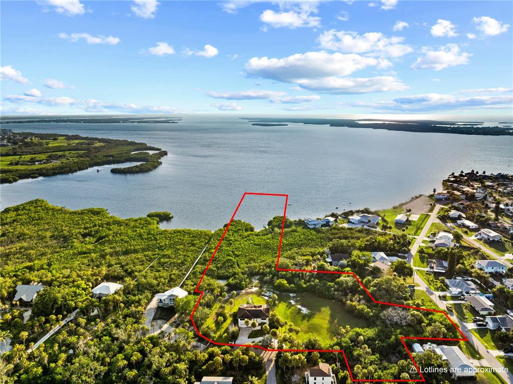 An aerial view shows a waterfront property with a house surrounded by dense vegetation — 609 42ND STREET COURT W, PALMETTO, FL