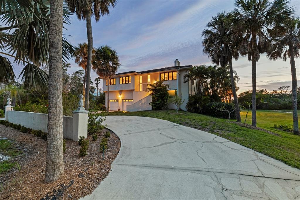 A two-story house with a curved concrete driveway and palm trees at dusk — 609 42ND STREET COURT W, PALMETTO, FL