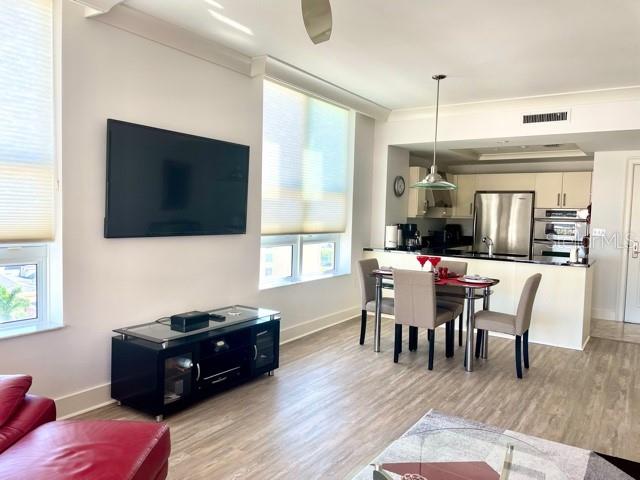 A modern living room features a wall-mounted television, a black media console, and an open kitchen — 1350 MAIN STREET UNIT 909, SARASOTA, FL