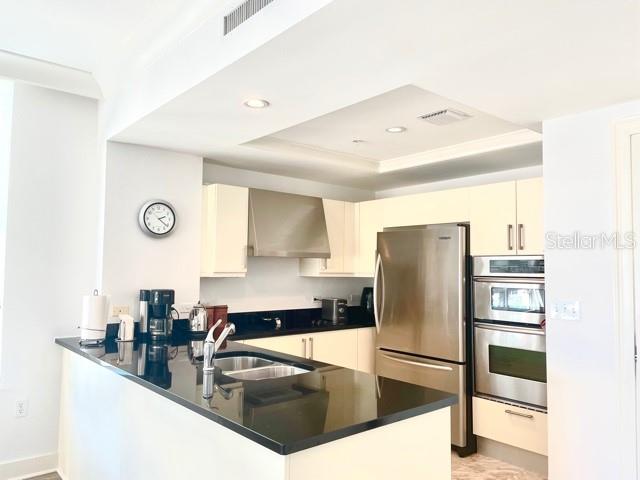 A kitchen features light-colored cabinetry, stainless steel appliances, and a black countertop island — 1350 MAIN STREET UNIT 909, SARASOTA, FL