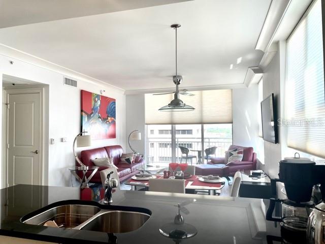 A modern kitchen island with a double sink overlooks a living room with red furniture — 1350 MAIN STREET UNIT 909, SARASOTA, FL