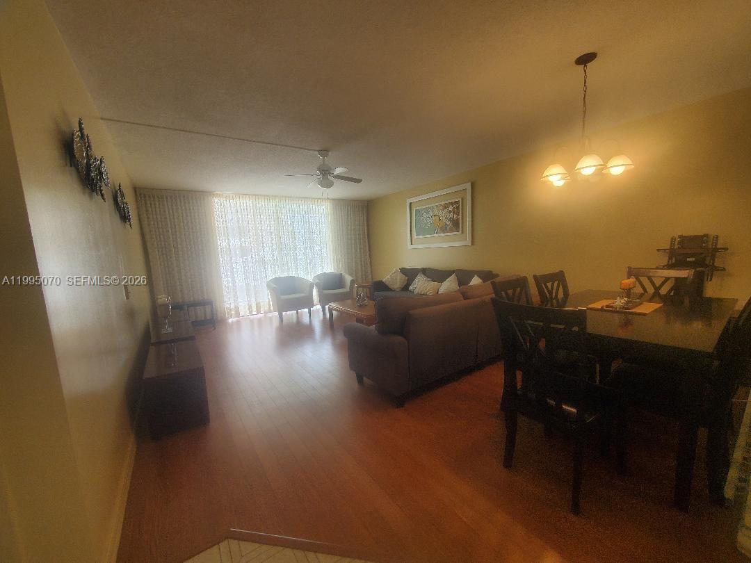 A living and dining area features wood-look flooring, a ceiling fan, and sliding glass doors — 319 NE 14th Ave # 207, Hallandale Beach FL 33009, HALLANDALE BEACH, FL