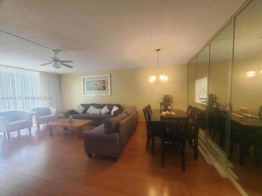 A living and dining area features wood flooring, a ceiling fan, and mirrored walls — 319 NE 14th Ave # 207, Hallandale Beach FL 33009, HALLANDALE BEACH, FL