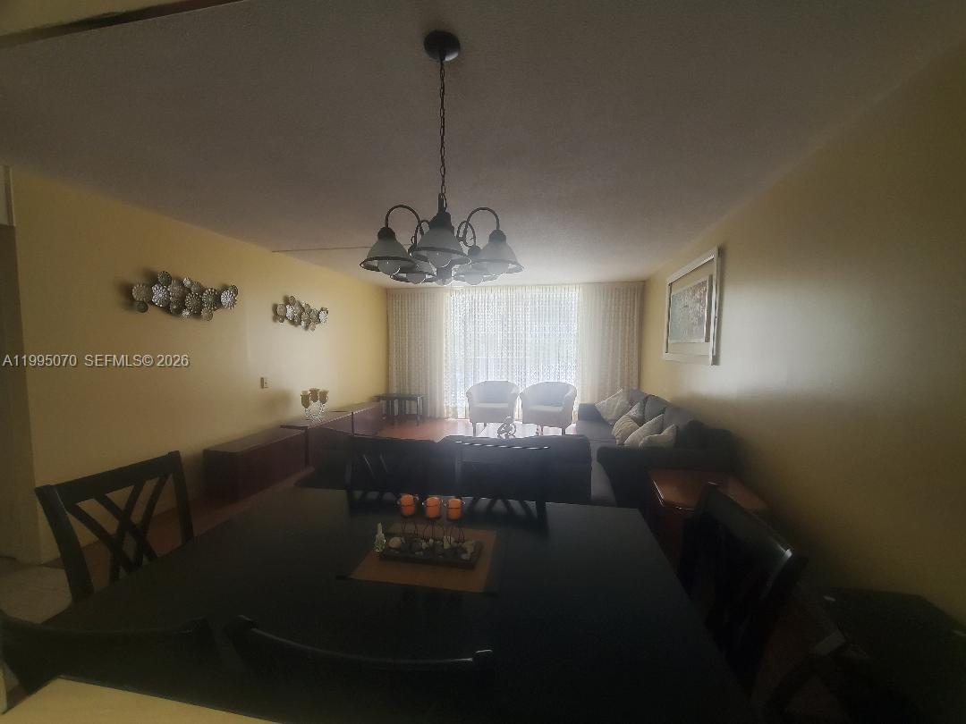 A dining area in the foreground opens into a living room with a chandelier — 319 NE 14th Ave # 207, Hallandale Beach FL 33009, HALLANDALE BEACH, FL