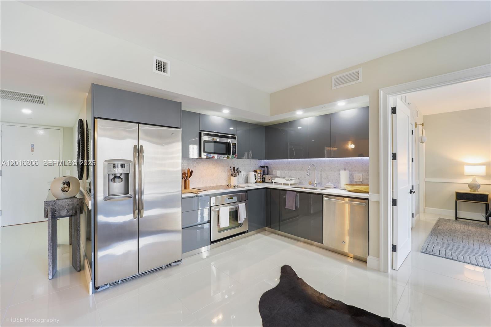 A modern kitchen features gray high-gloss cabinets, stainless steel appliances, and white tile flooring — 31 SE 6th St # 2207, Miami FL 33131, MIAMI, FL