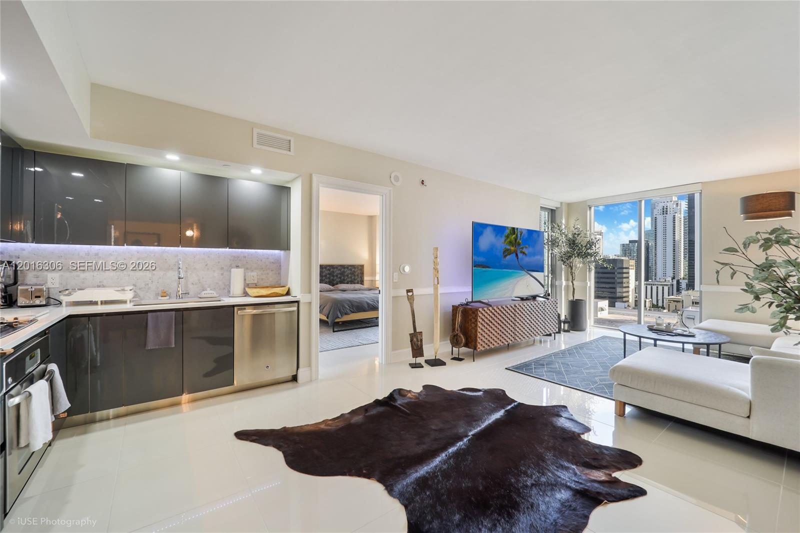 A modern open-concept living area features a kitchen with dark cabinets and city views — 31 SE 6th St # 2207, Miami FL 33131, MIAMI, FL