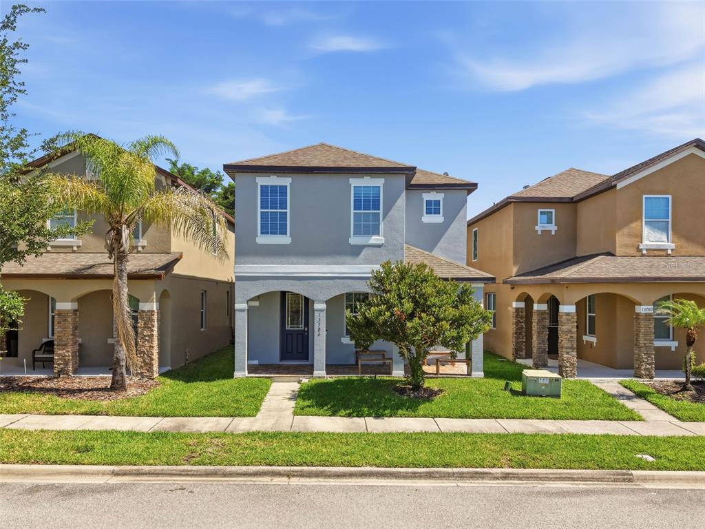 A two-story gray house with a covered front porch sits between two tan houses — 13786 SUMMER HARBOR COURT, WINDERMERE, FL