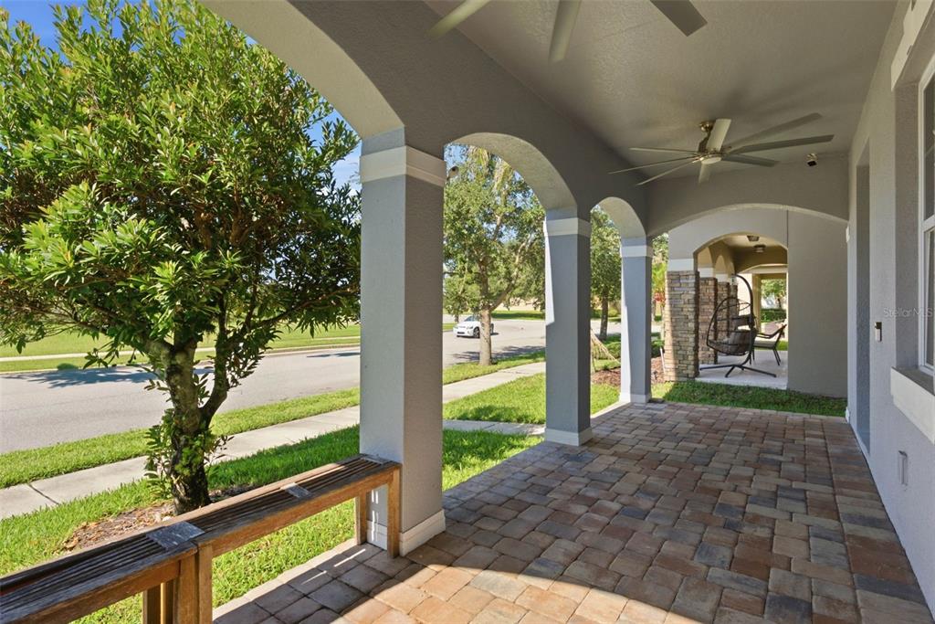 A covered front porch features arched columns, a paver floor, and a wooden bench — 13786 SUMMER HARBOR COURT, WINDERMERE, FL
