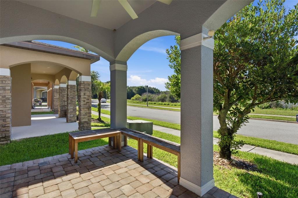 A covered patio with stone pavers, wooden benches, and arched columns overlooks a suburban street — 13786 SUMMER HARBOR COURT, WINDERMERE, FL