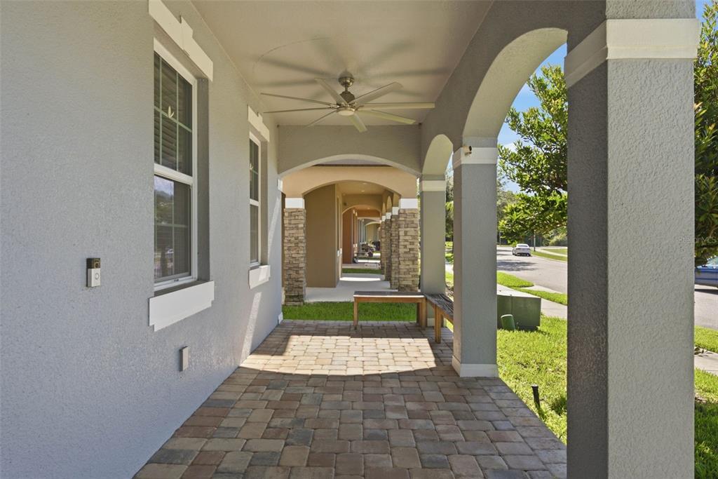 A covered porch features stone-accented columns, a ceiling fan, and a paved brick floor — 13786 SUMMER HARBOR COURT, WINDERMERE, FL