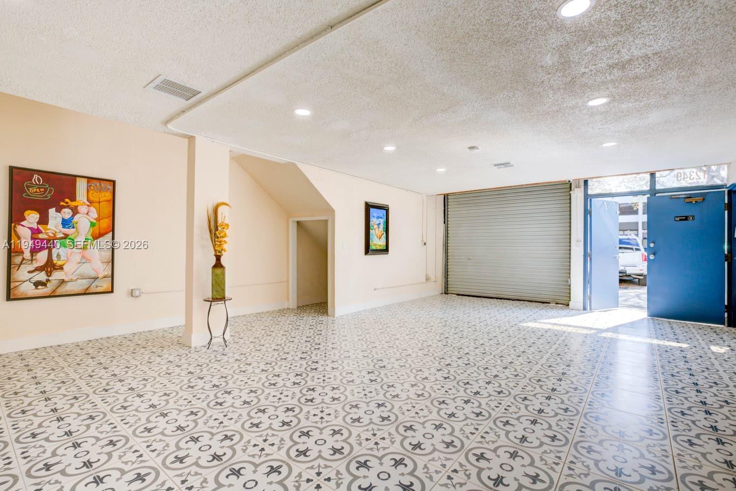 An interior space with patterned tile flooring, a roll-up metal door, and a blue door — 12349 SW 132nd Ct # 9, Miami FL 33186, MIAMI, FL