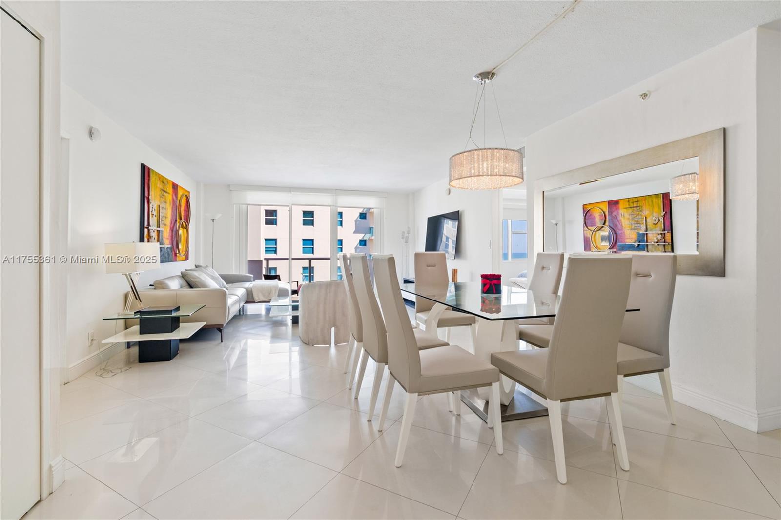 A bright dining and living area features white tile floors, modern furniture, and a chandelier — 9195 Collins Ave # 1103, Surfside FL 33154, SURFSIDE, FL