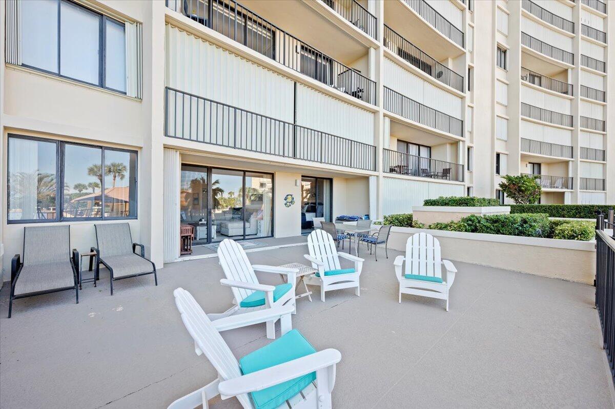 A spacious outdoor patio features several white Adirondack chairs and a dining set — 100 Ocean Trail Way # 107, Jupiter FL 33477, JUPITER, FL