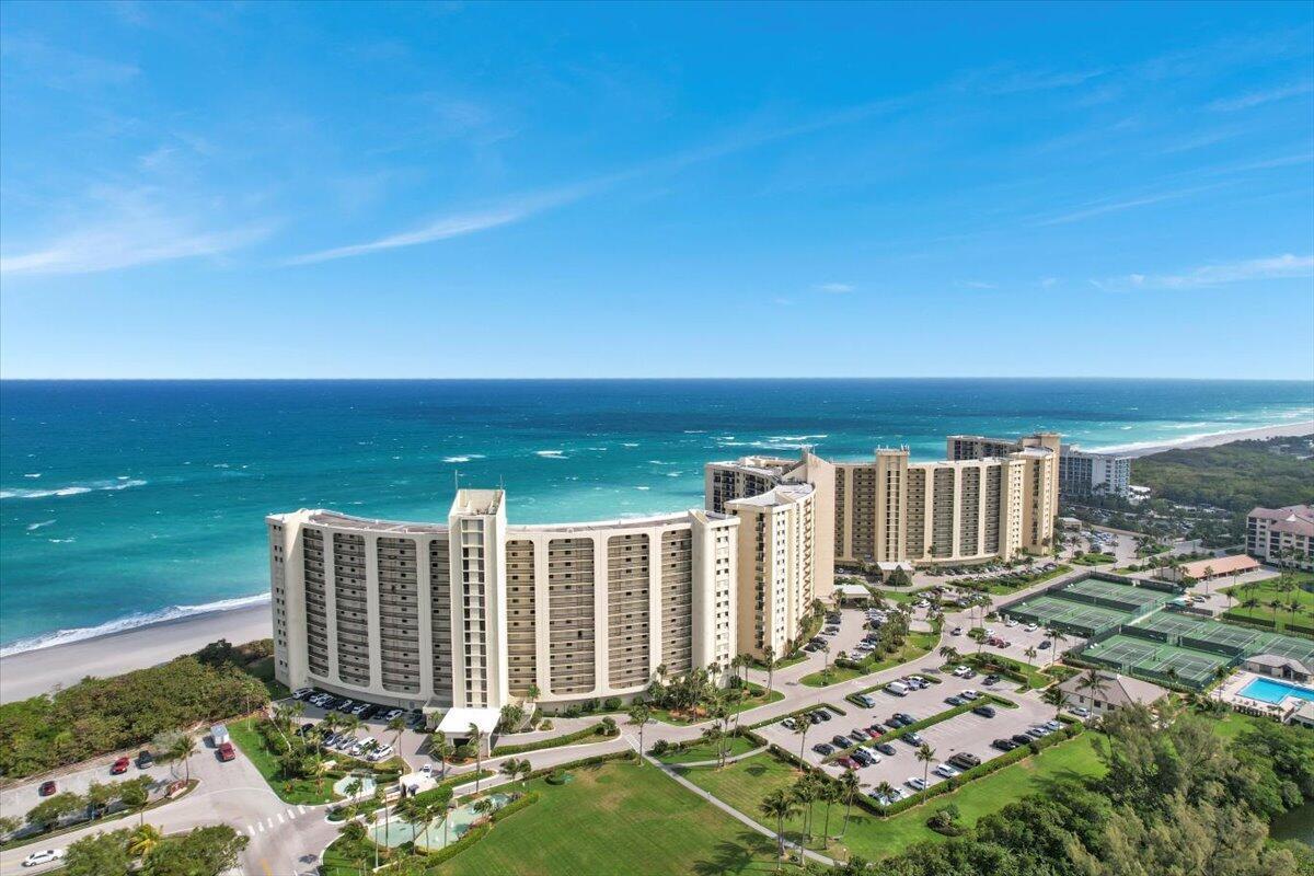 An aerial view shows a large beachfront apartment complex with tennis courts and parking lots — 100 Ocean Trail Way # 107, Jupiter FL 33477, JUPITER, FL