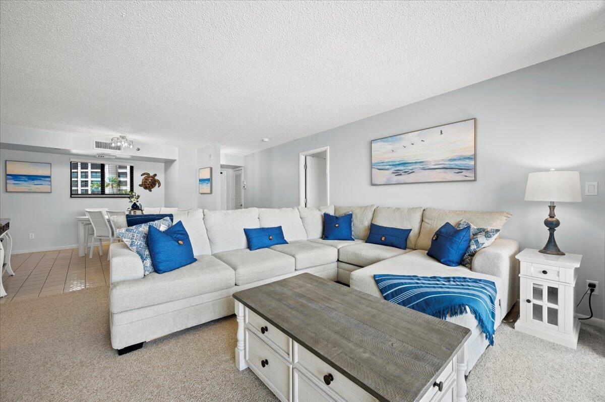 A living room features a large sectional sofa, a coffee table, and coastal-themed wall art — 100 Ocean Trail Way # 107, Jupiter FL 33477, JUPITER, FL