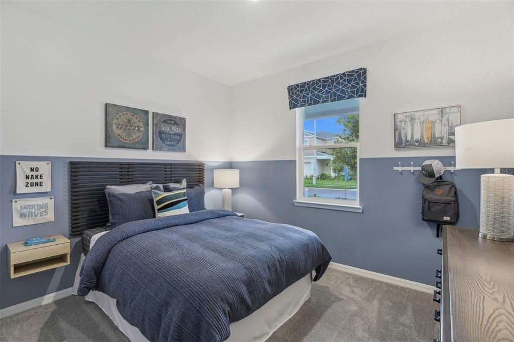 A bedroom features blue and white walls, a dark slatted headboard, and surf-themed decor — 1409 CHAMBORD DRIVE, EAGLE LAKE, FL