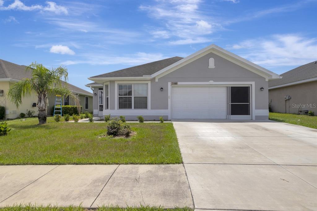 A single-story house with a gray exterior, a two-car garage, and a front lawn — 7088 WIREVINE DRIVE, BROOKSVILLE, FL