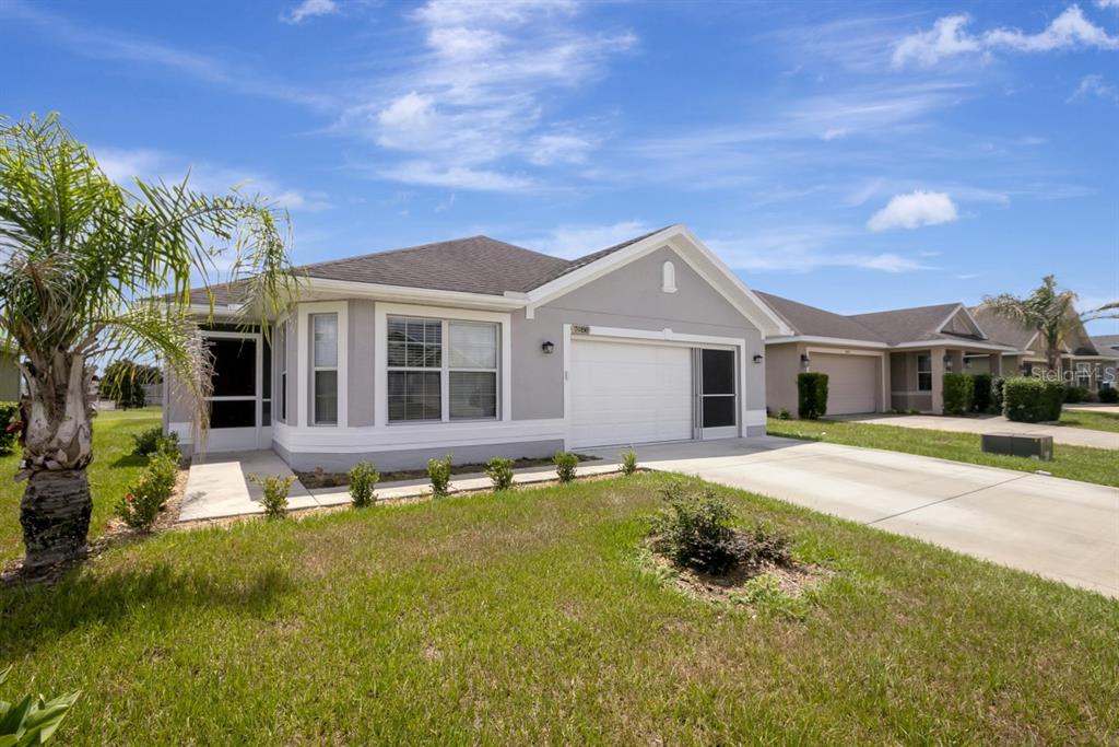 A single-story gray house with a white garage door and a palm tree in front — 7088 WIREVINE DRIVE, BROOKSVILLE, FL