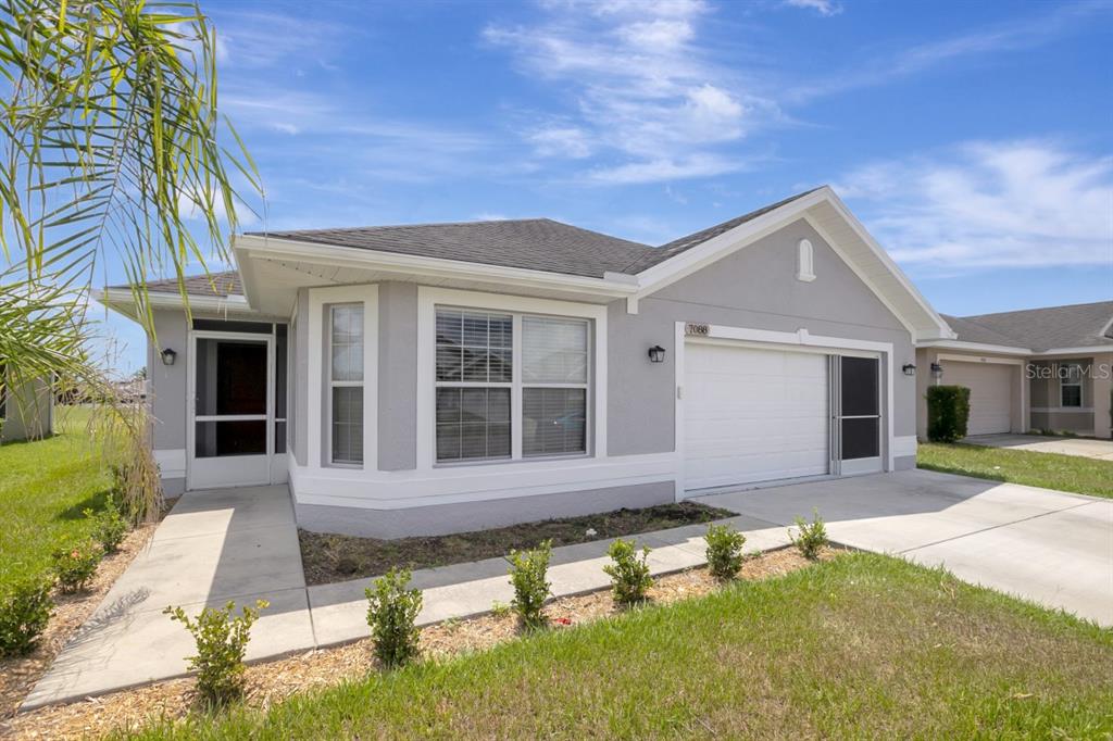 A single-story gray house with a white garage door and a front walkway — 7088 WIREVINE DRIVE, BROOKSVILLE, FL