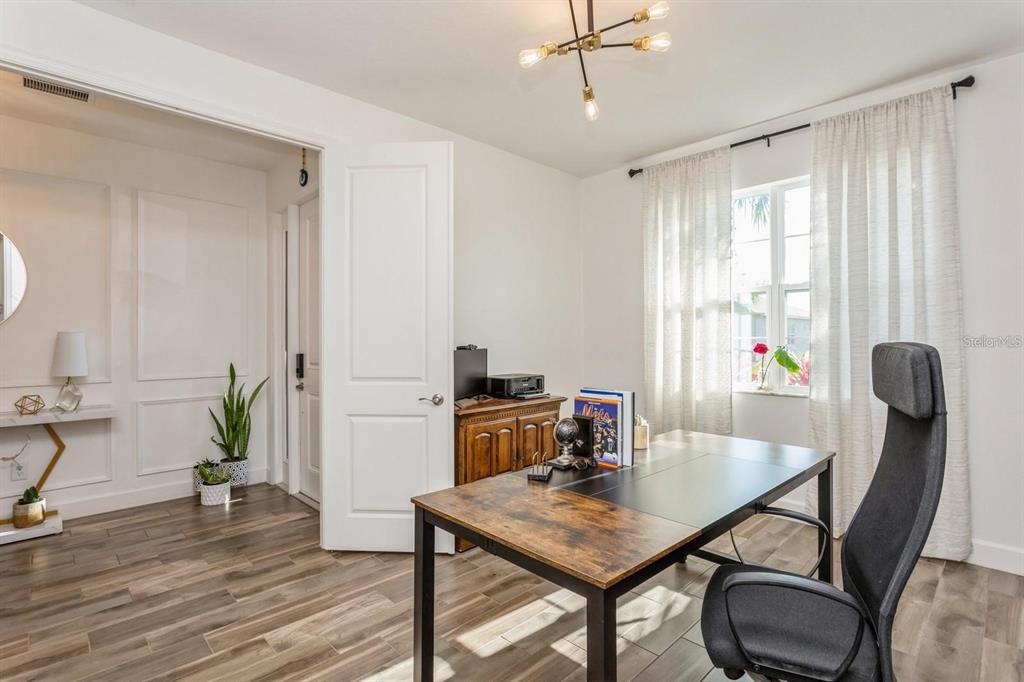 A home office features a wooden desk, a black chair, and white paneled walls — 3281 GREAT BANYAN WAY, WESLEY CHAPEL, FL