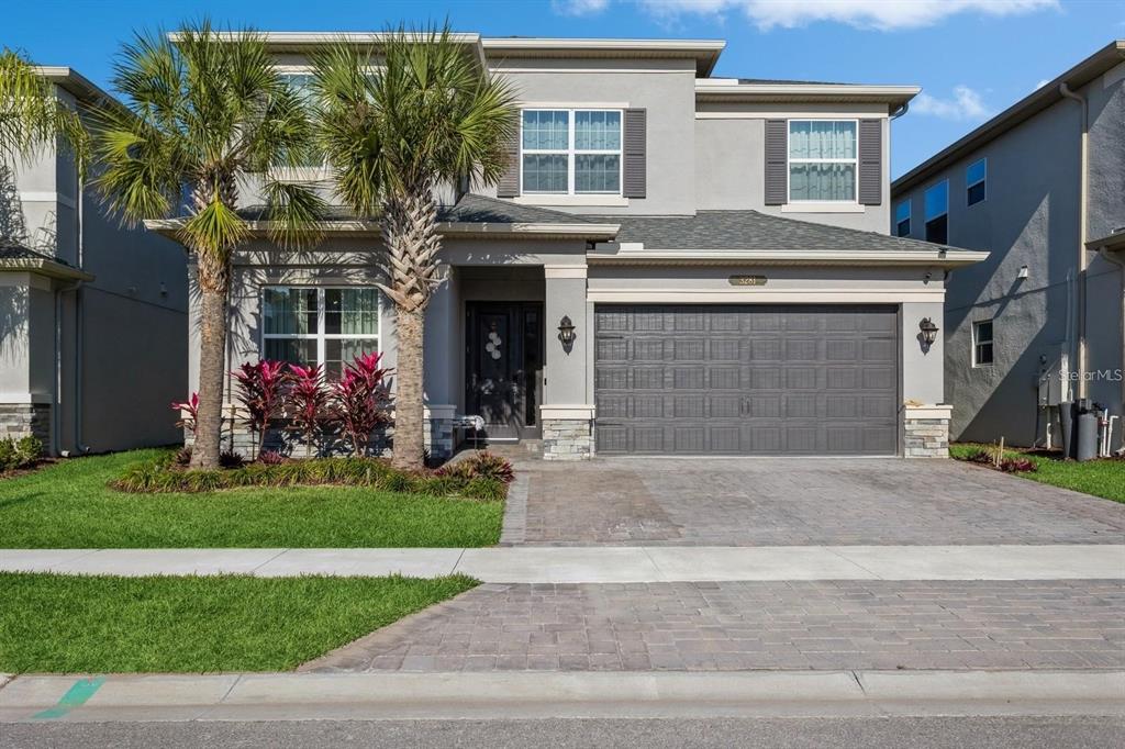 A two-story gray house with a two-car garage, palm trees, and a paved driveway — 3281 GREAT BANYAN WAY, WESLEY CHAPEL, FL