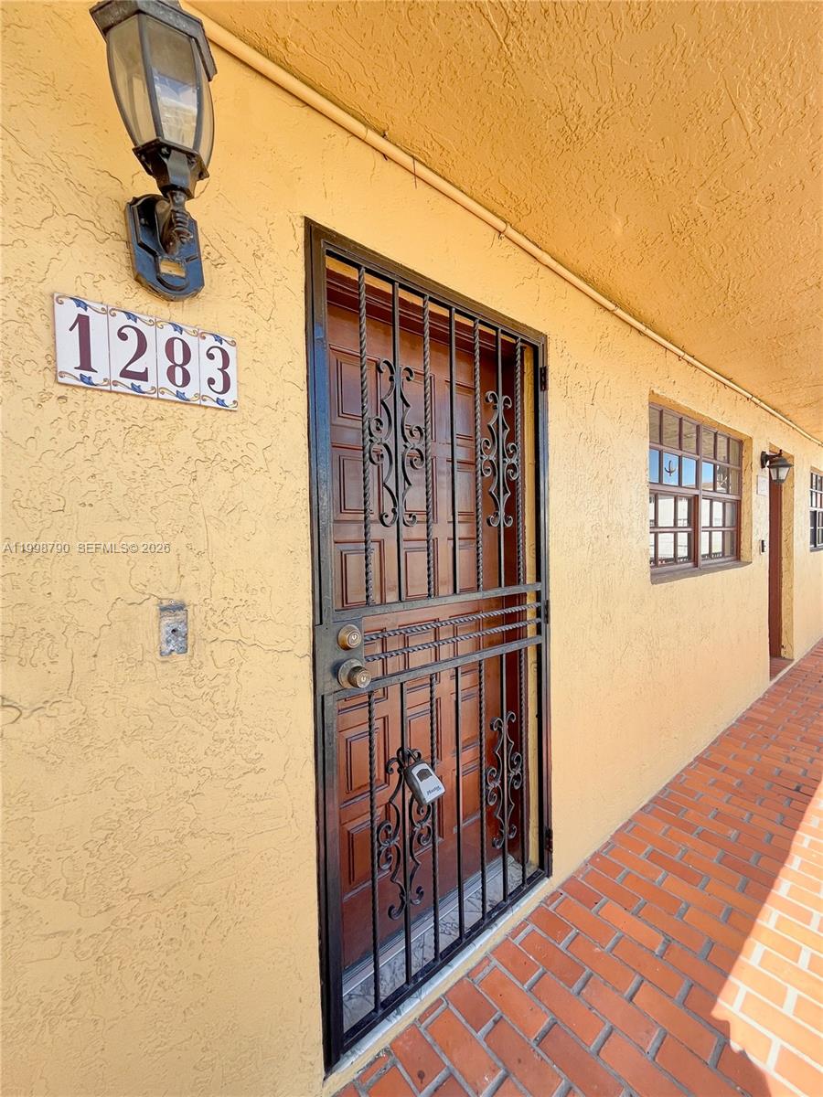An exterior view of a building entrance with a security door and house number 1283 — 1283 W 51st Place # 12, Hialeah FL 33012, HIALEAH, FL