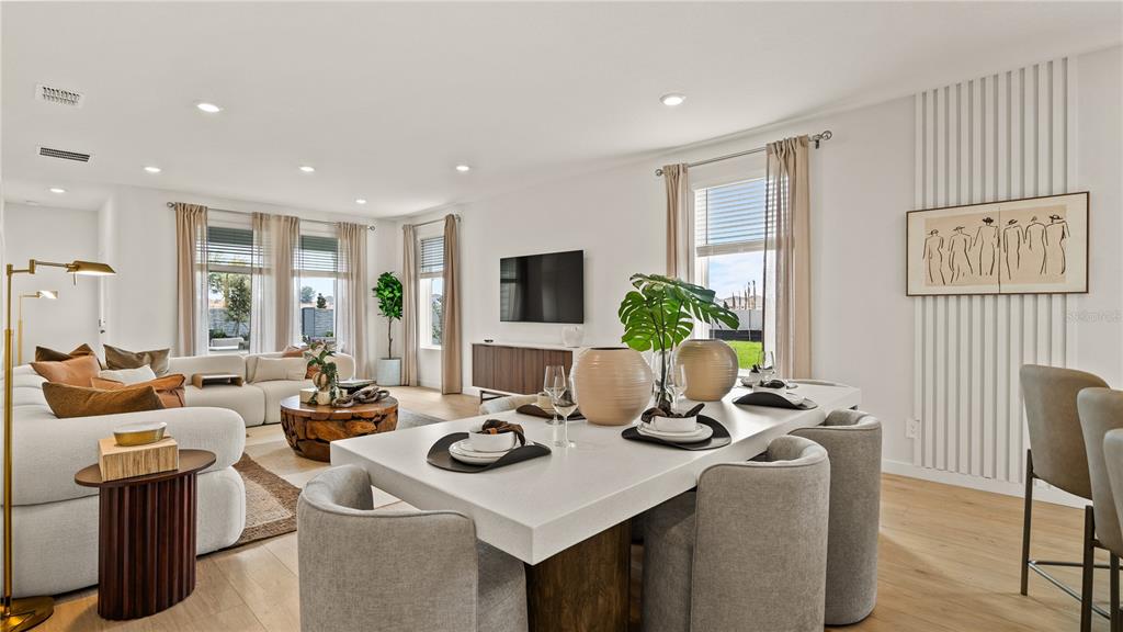 An open-concept living and dining area features modern furniture, neutral tones, and large windows — 1941 FIELDSTONE STREET, MINNEOLA, FL