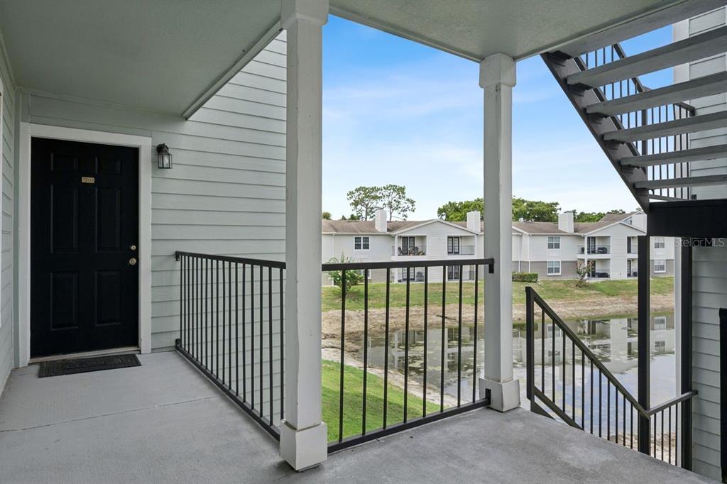 An exterior view of an apartment balcony overlooking a pond and neighboring residential buildings — 2550 N ALAFAYA TRAIL UNIT 7203, ORLANDO, FL