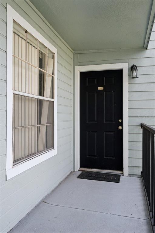 A black front door with a house number sits next to a window on a porch — 2550 N ALAFAYA TRAIL UNIT 7203, ORLANDO, FL
