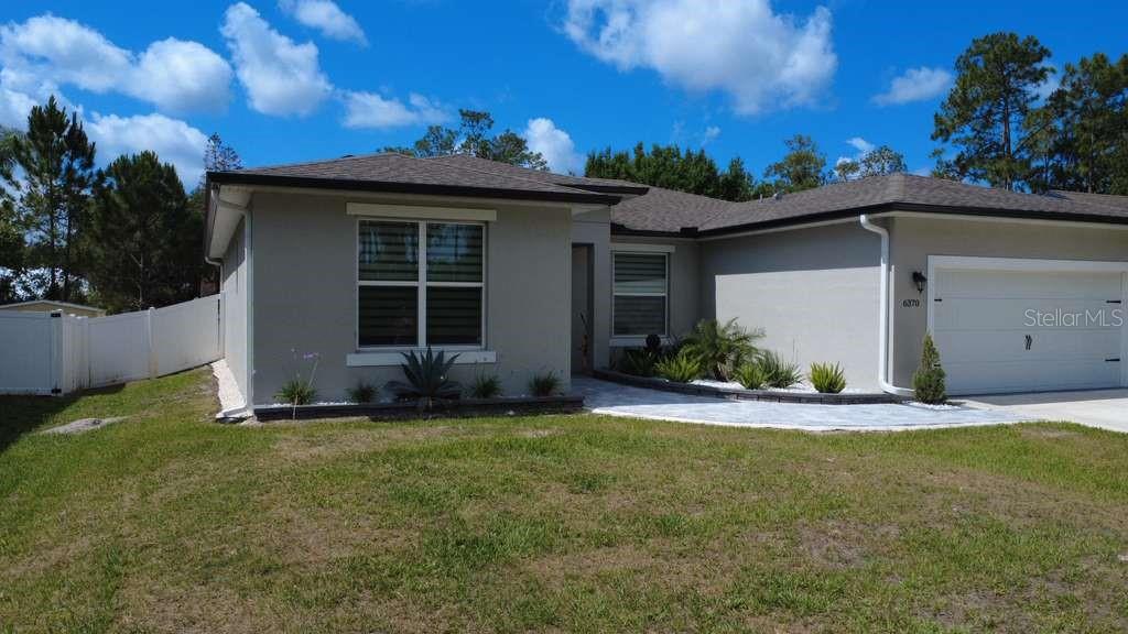 A single-story house with a gray exterior, a two-car garage, and a white fence — 6370 BENNETT COURT, ST CLOUD, FL