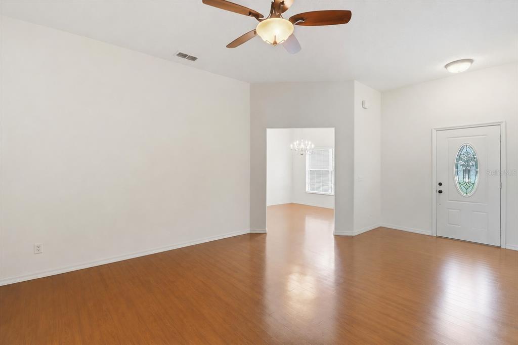 An empty living room features wood-look flooring, a ceiling fan, and a white front door — 6347 N MYAKA AVENUE, CRYSTAL RIVER, FL