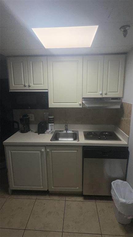 A small kitchen features off-white cabinets, a stainless steel sink, a stovetop, and a dishwasher — 6165 CARRIER DR DRIVE UNIT 1114, ORLANDO, FL