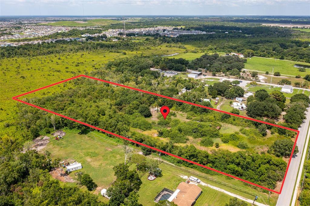 An aerial view shows a rectangular plot of land outlined in red near a road — 10800 BILL TUCKER ROAD, WIMAUMA, FL