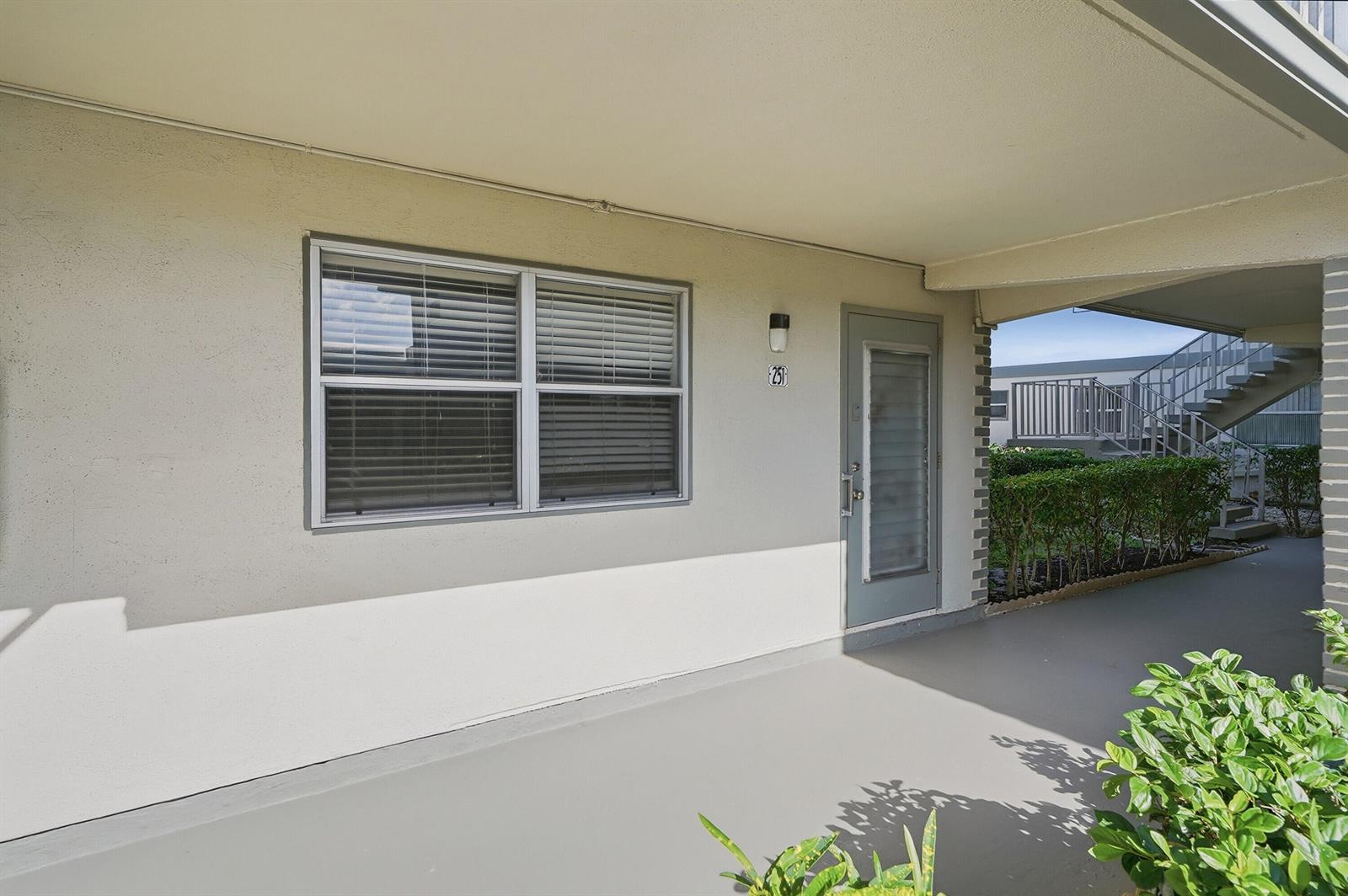 The exterior view shows a ground-level apartment entrance with a window and a gray door — 251 Monaco Way, Delray Beach FL 33446, DELRAY BEACH, FL