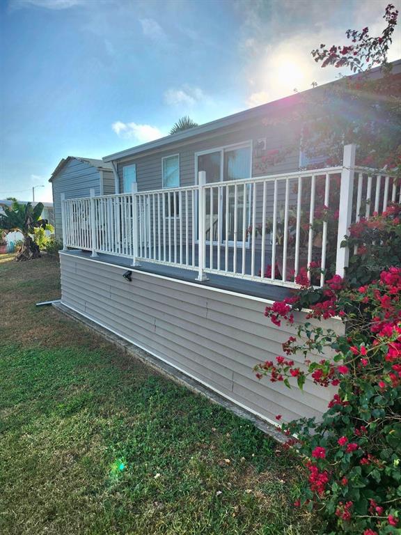 A raised deck with white railings sits alongside a house with gray horizontal siding — 6505 ARIZONA STREET, BRADENTON, FL
