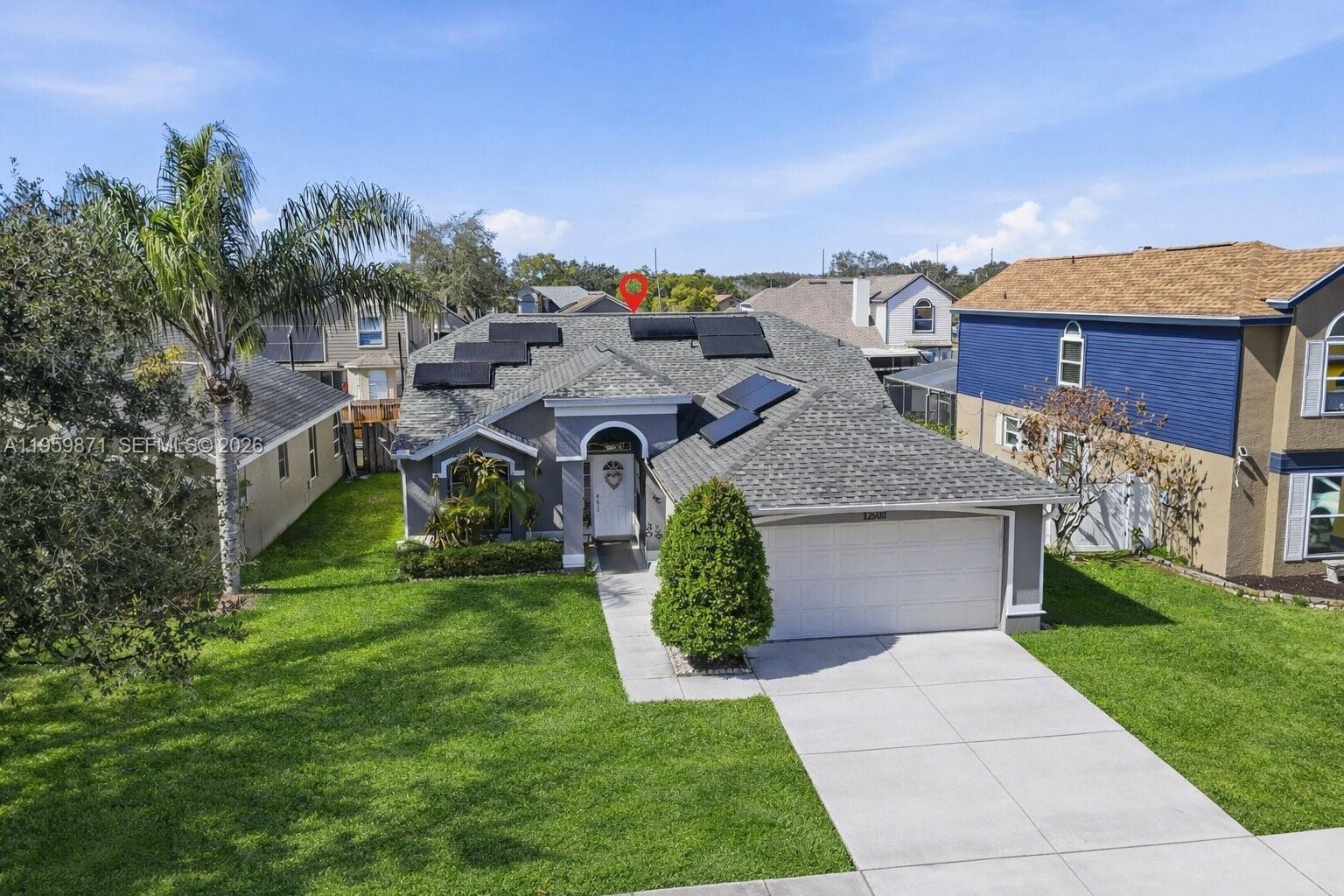 An exterior view of a single-story house with a shingled roof and solar panels — 12608 Crayford ave, Orlando FL 32837, ORLANDO, FL