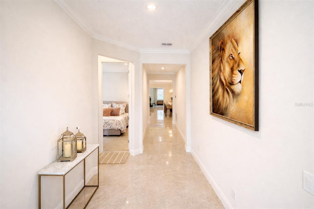A bright hallway with tile floors, a lion painting, and a view into a bedroom — 9241 PATRIMONIO LOOP, WINDERMERE, FL