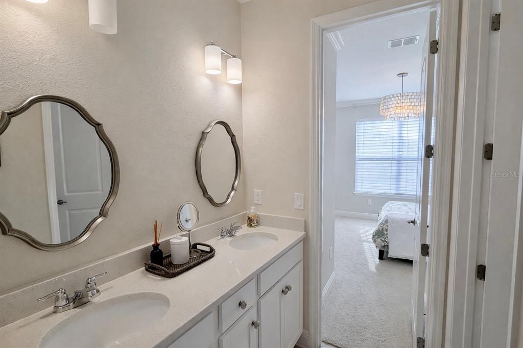 A bathroom features a double vanity with white cabinets, quartz countertops, and two oval mirrors — 9241 PATRIMONIO LOOP, WINDERMERE, FL