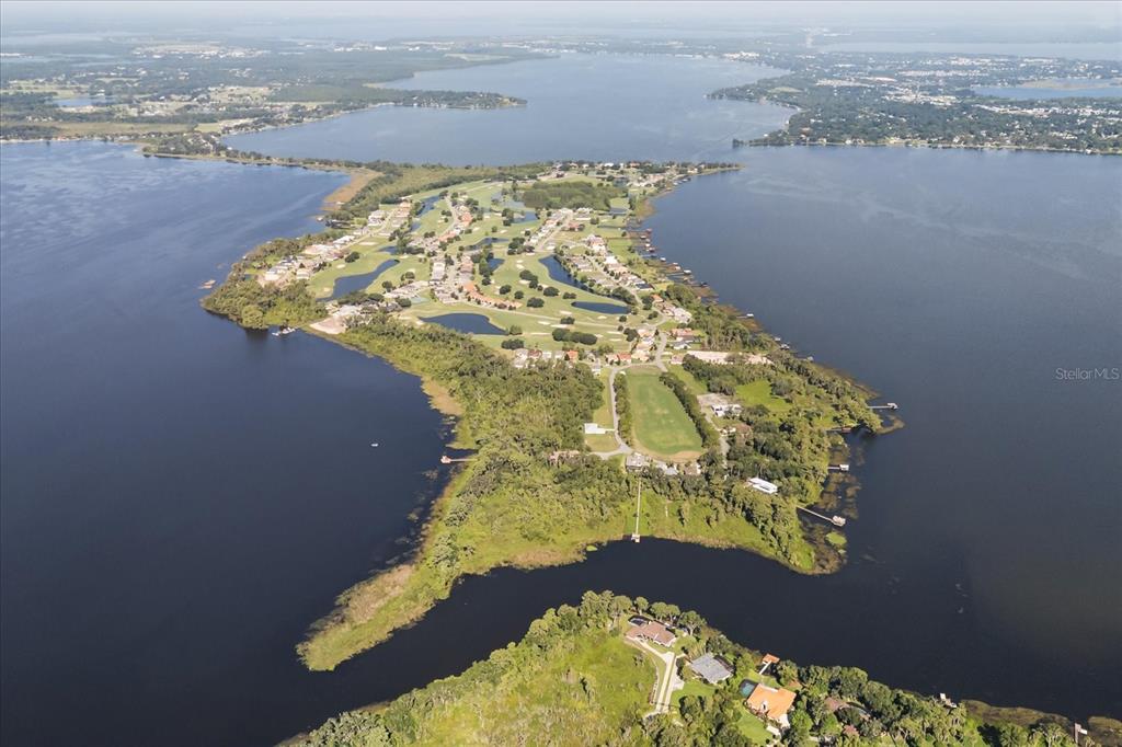 An aerial view shows a residential community located on a peninsula surrounded by a lake — LOT C-28 SAWGRASS RUN, TAVARES, FL