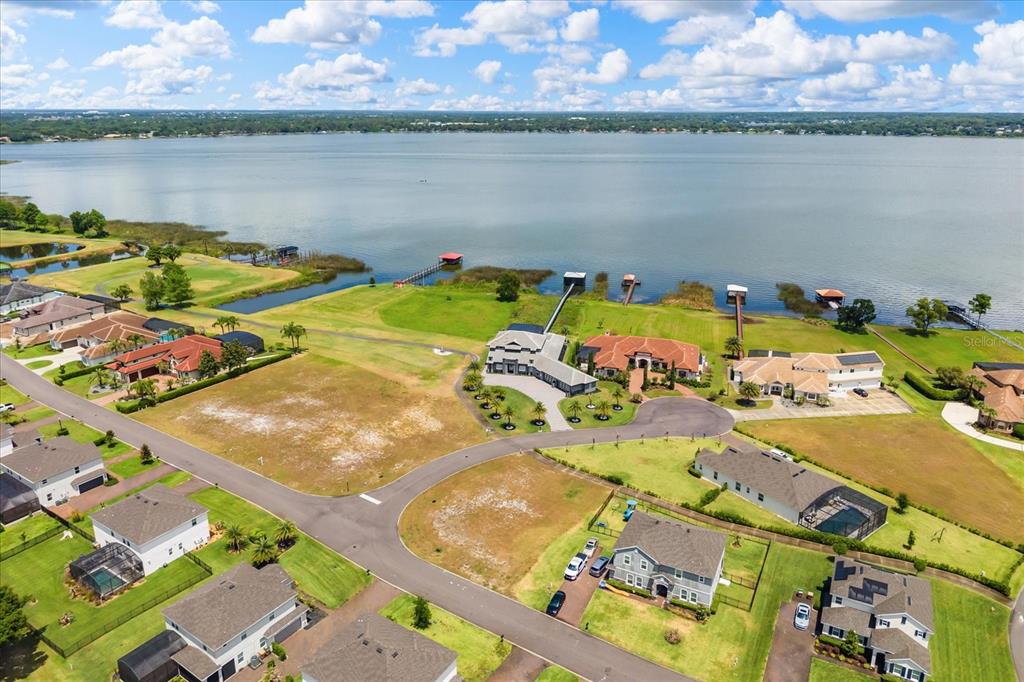 An aerial view shows several houses situated along a large lake with private docks — LOT C-28 SAWGRASS RUN, TAVARES, FL