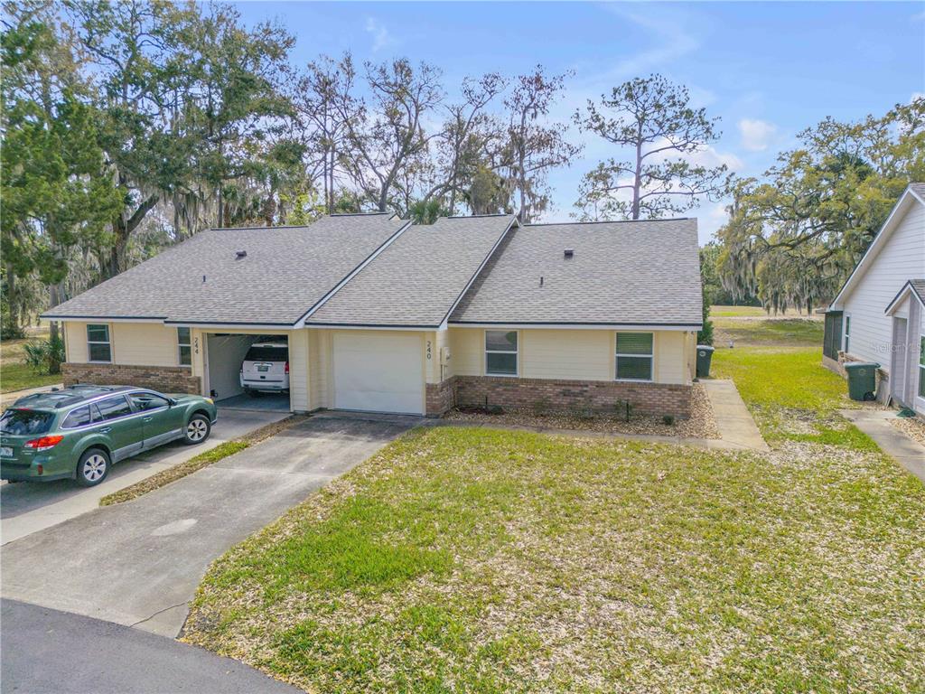 A duplex building with light yellow siding, brick accents, and two attached garages — 240 BOB WHITE COURT UNIT 240, DAYTONA BEACH, FL