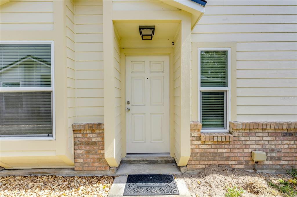 The exterior of a house features a white front door, light siding, and brick accents — 240 BOB WHITE COURT UNIT 240, DAYTONA BEACH, FL