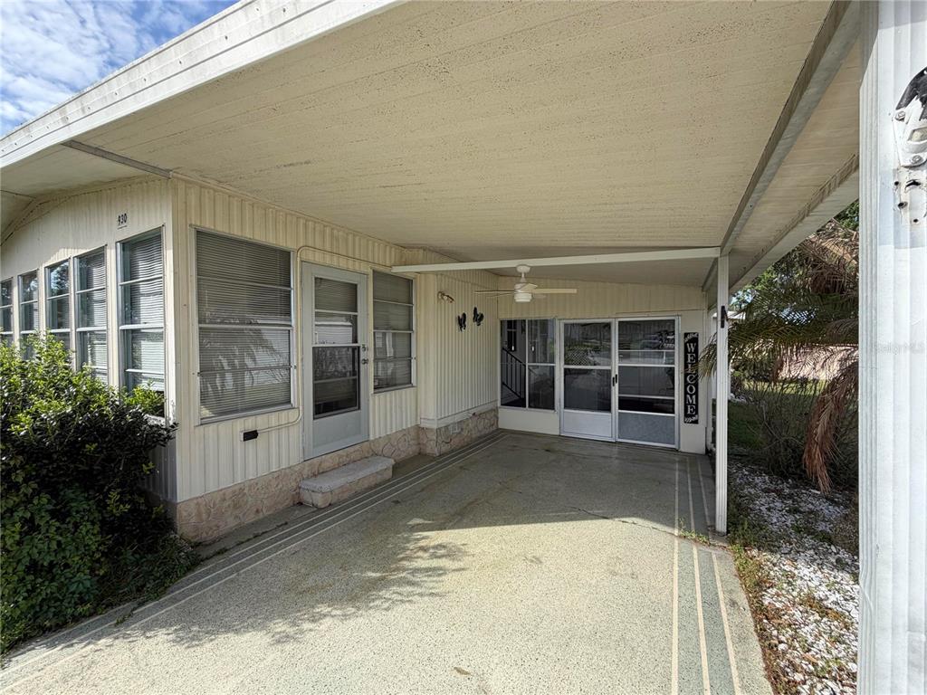 A covered carport with a concrete floor leads to a home entrance and screened porch — 930 TARRSON BOULEVARD, LADY LAKE, FL