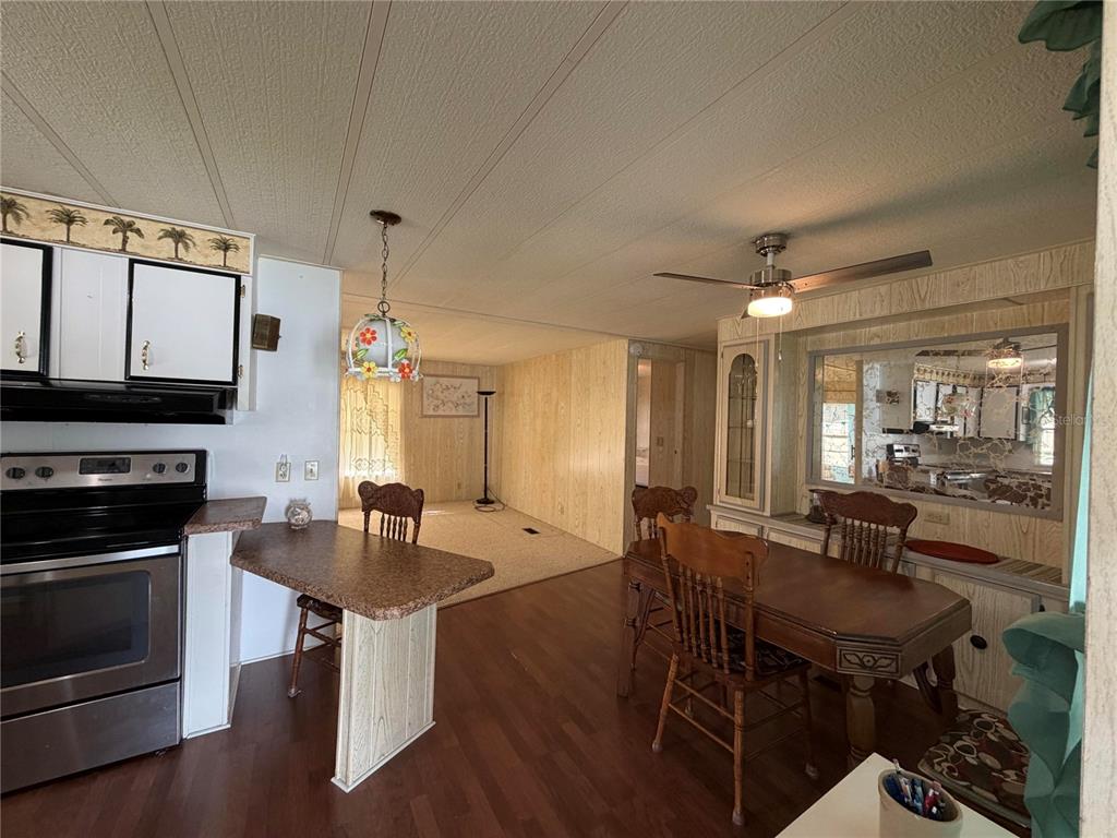 A kitchen and dining area features wood-paneled walls, laminate flooring, and a small breakfast bar — 930 TARRSON BOULEVARD, LADY LAKE, FL