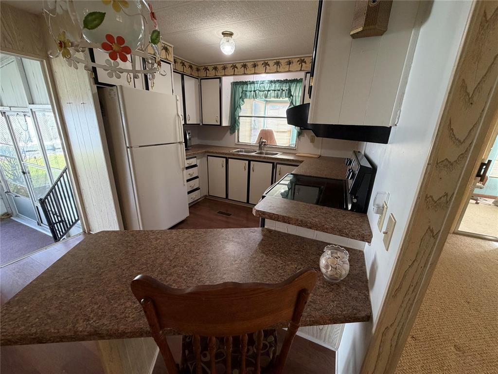 A kitchen with white cabinets, brown countertops, a white refrigerator, and a small breakfast bar — 930 TARRSON BOULEVARD, LADY LAKE, FL